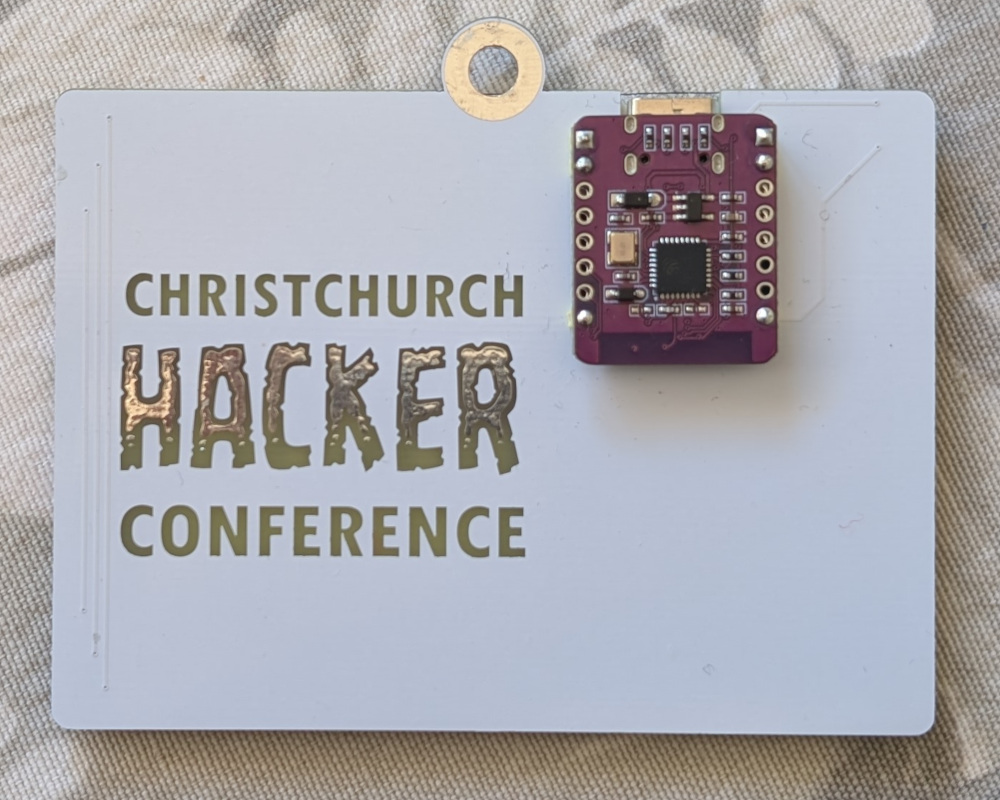 Back side of a circuit board conference attendee badge, showing a mounted ESP32